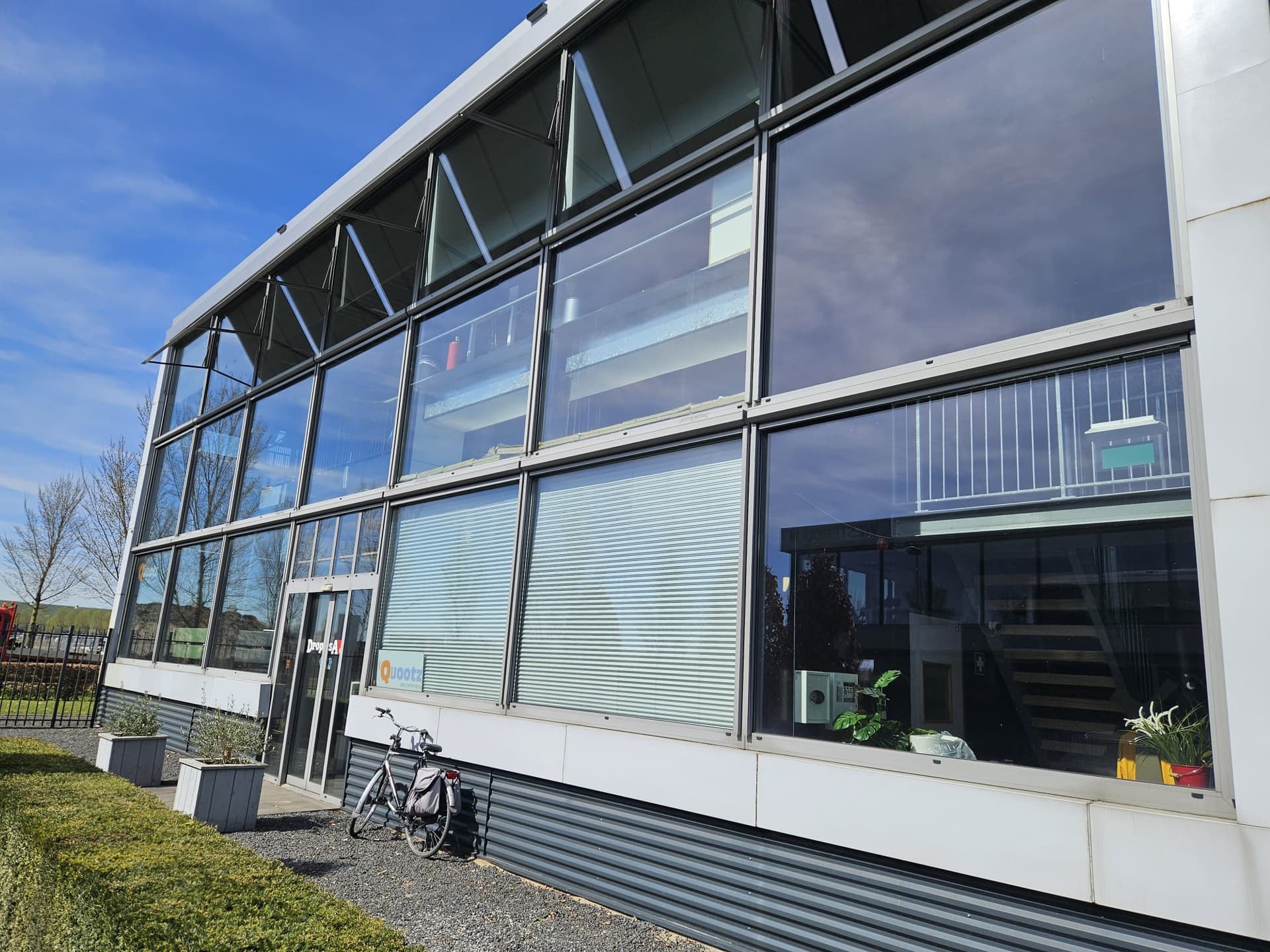 Streepvrij gereinigde glazen pui en entree van een bedrijfspand in Apeldoorn na etalagereiniging door Madern