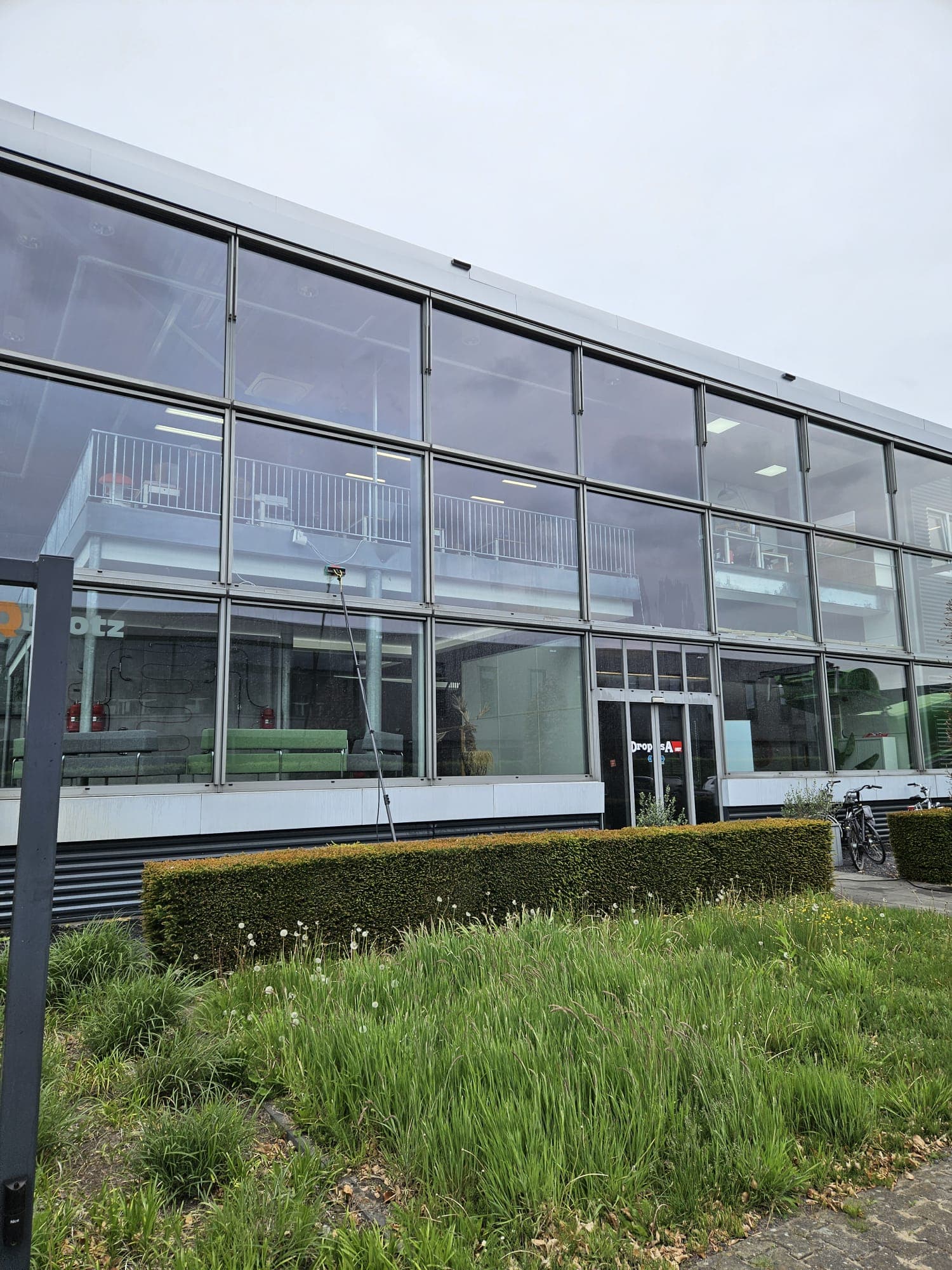 Glasbewassing van de glasgevel van een kantoorpand in Apeldoorn met een watergevoede telescoopsteel op osmosewater