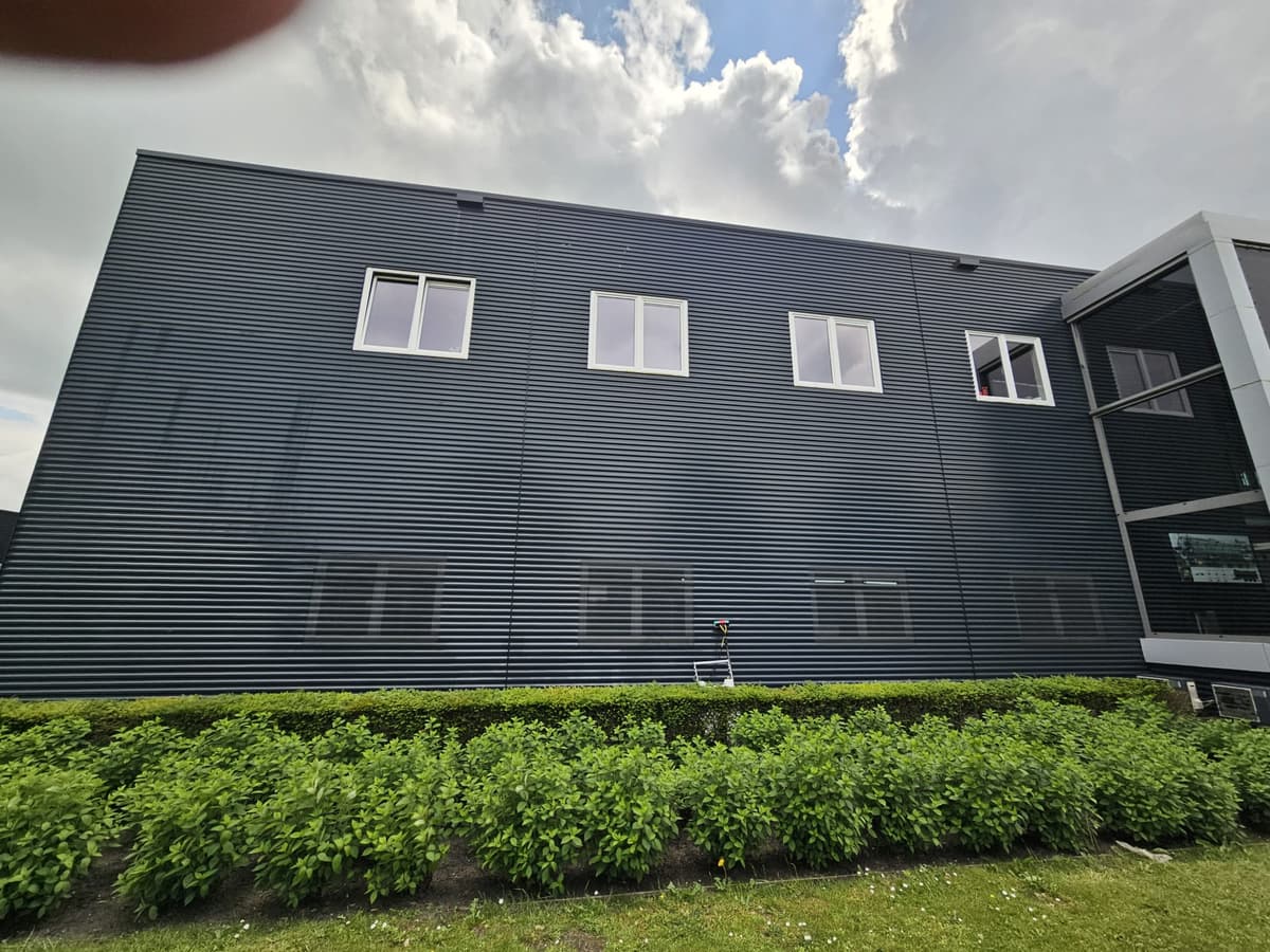 Watergevoede telescoopsteel tegen de gevel van een bedrijfspand bij Apeldoorn tijdens de glasbewassing
