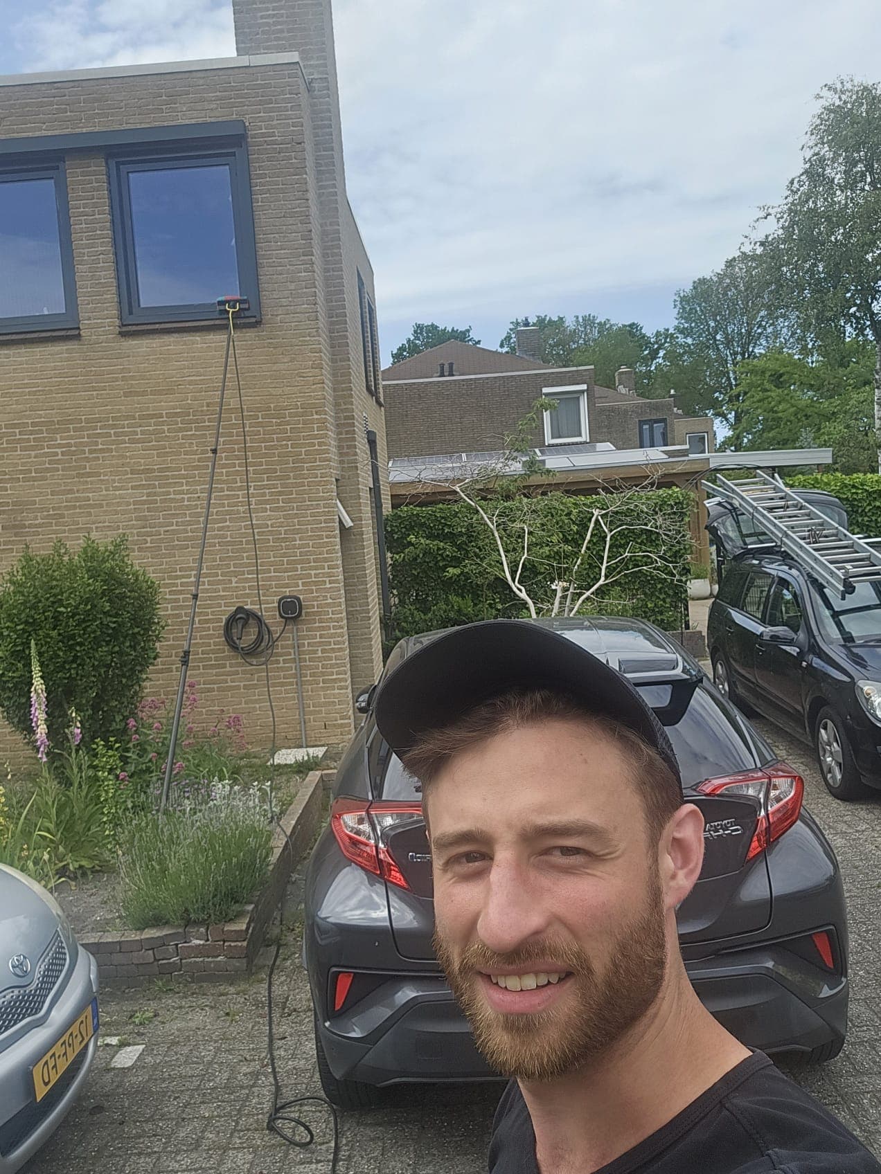Michael, oprichter en glazenwasser van Madern Glazenwassers, bij een woning in Apeldoorn met de telescoopsteel en bedrijfsbus achter zich